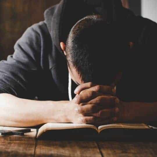 cry during prayer - humility before God - man facedown praying on Bible